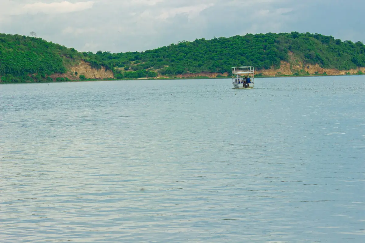 A small boat on calm blue water between green hills