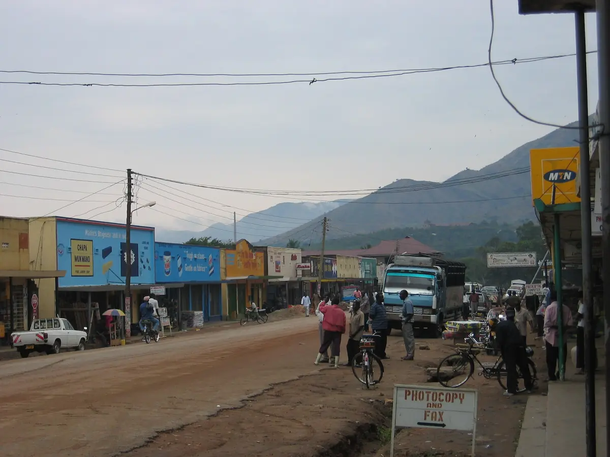 Een straat in Kasese met winkels en het Rwenzorigebergte in de verte