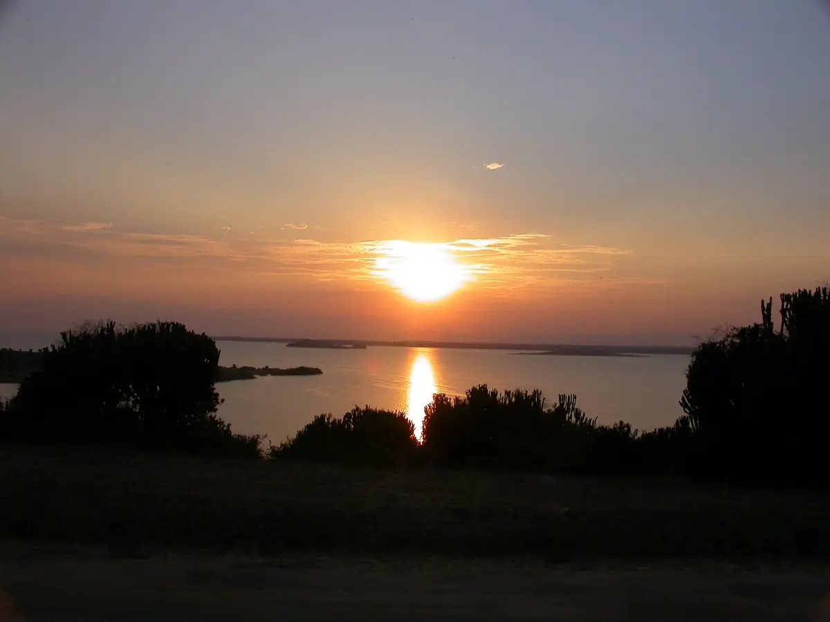 The sun setting over Lake Edward with trees in silhouette